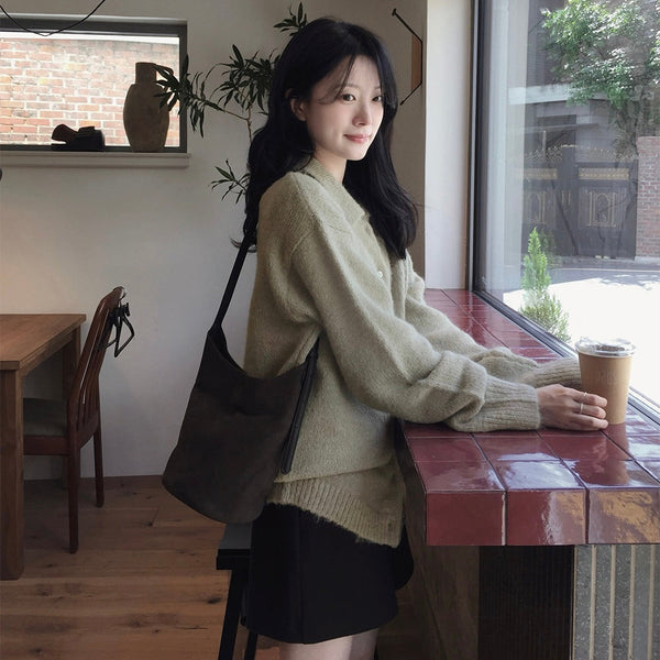 SLOWAND 灰卡其針織外套側面穿搭，模特兒站於咖啡店窗邊，展示落肩剪裁及寬鬆袖型。